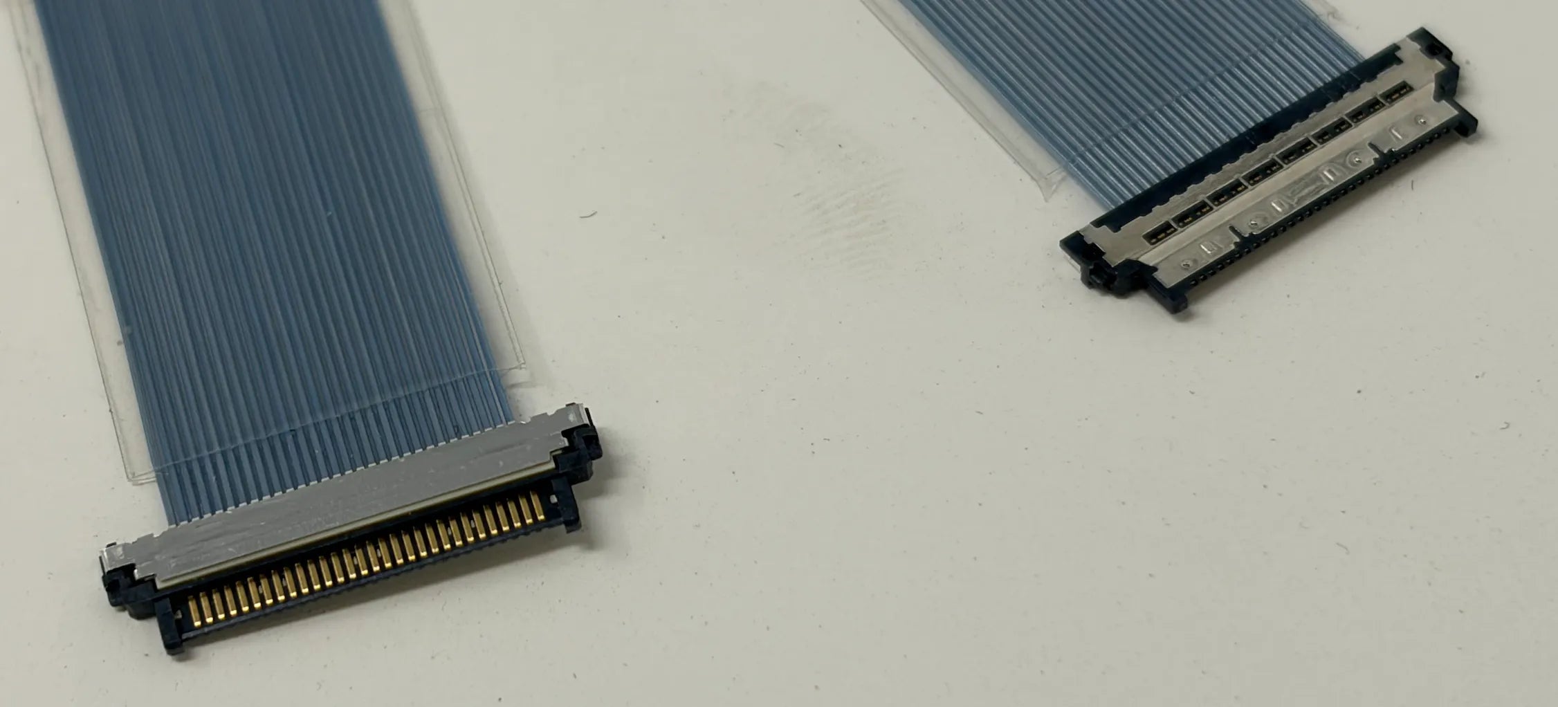 Two micro coaxial connectors with blue flex cables on a white background