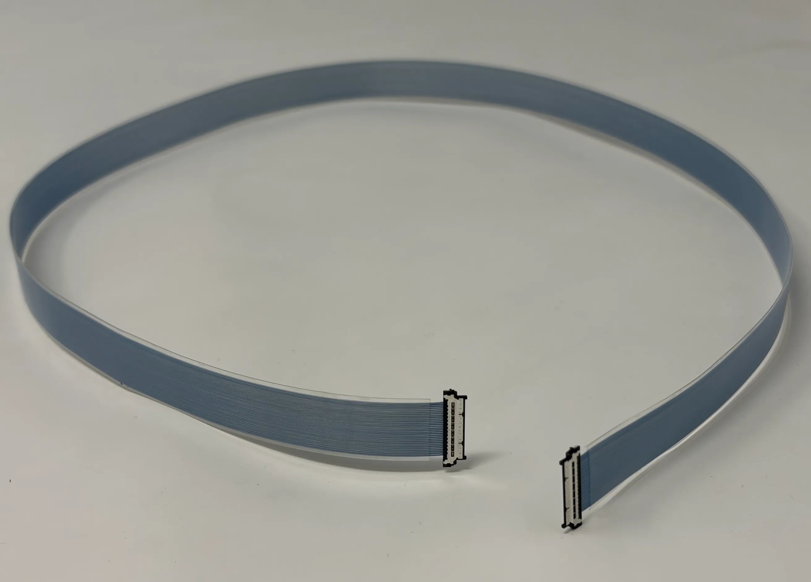 Gray flat micro coaxial cable with connectors on a white background