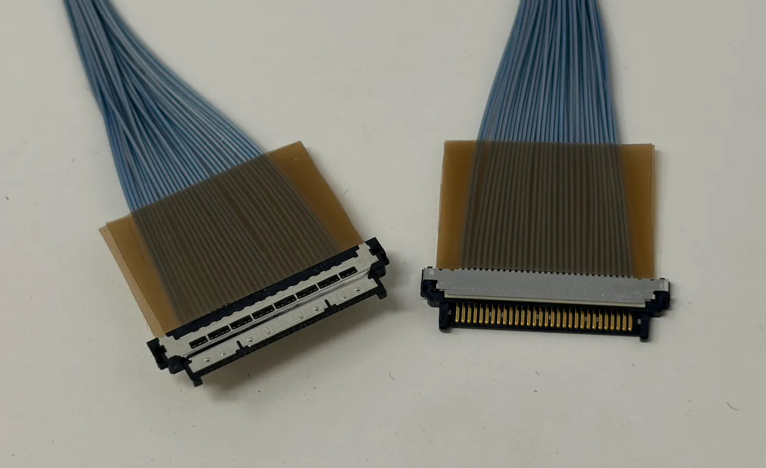 Two micro coaxial connectors with blue wires on a white background